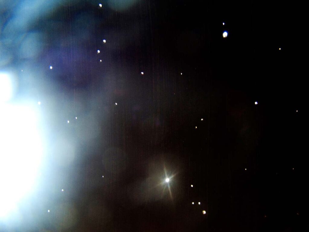 View of space showing various white stars of different sizes on a dark background in the website footer.