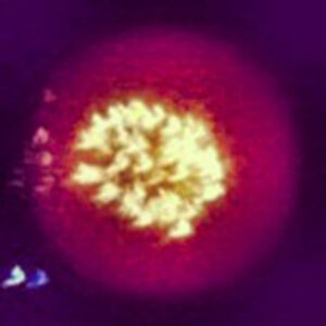 Bright yellow explosion against a dark purple background, with blurred edges and scattered light patterns surrounding the central burst.