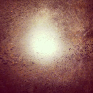 A close-up of a brown, speckled surface with a bright circular light reflection in the center.