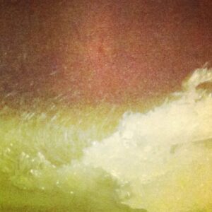 A close-up view of frothy, white ocean waves crashing onto a green-tinted shore under a reddish-brown sky.